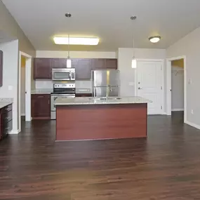 A kitchen with dark wood floors and white walls.
