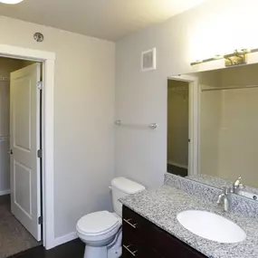 A bathroom with a toilet, sink, and mirror.