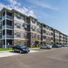 an apartment building with cars parked in a parking lot