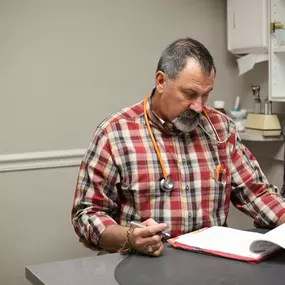 “Dr. Wade Matthews writes his exam findings in his patient’s health records.  It’s a clean bill of health for this pup!”