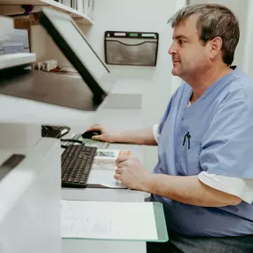 Jason, a veterinary technician, updates patient documents with a smile!