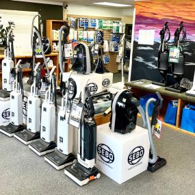 The Imperial Vacuum and Appliances showroom in Bozeman, Montana, displays a range of upright, canister, cordless, and robot vacuums. Shelves are stocked with various vacuum bags, showcasing a wide selection in a clean, professional setting.