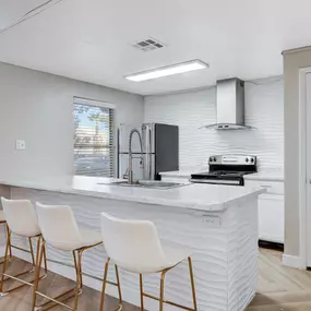 Clubroom kitchen with barstool seating and white countertops