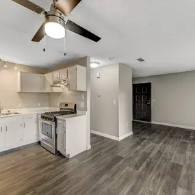 Open kitchen with updated flooring and ceiling fan