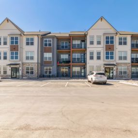 Exterior view of the apartment building with a parking lot in front of it