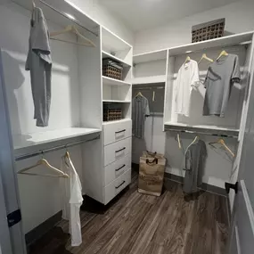 A walk-in closet with white cabinets