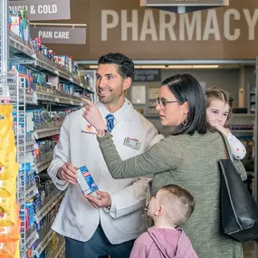 Customer with children asking advice from pharmacist in aisle.