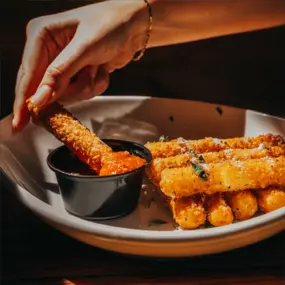 A plate of Mozzarella Sticks dipping in our warm marinara sauce