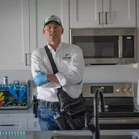 A professional First Line Pest Defense technician stands in a kitchen, ready to deliver effective pest control solutions.