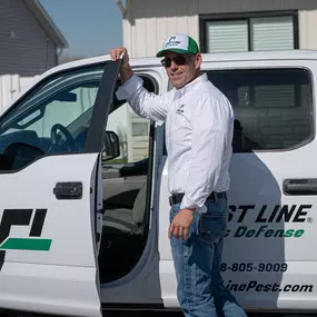 A friendly First Line Pest Defense technician standing proudly by their service truck, ready to help with pest issues.