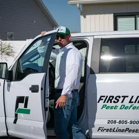 First Line Pest Defense technician standing beside their branded service truck, ready to provide expert pest eradication.