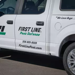 Close-up of the First Line Pest Defense truck with logo, phone number, and website visible.