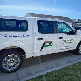 Side view of the First Line Pest Defense truck with company logo and slogan, providing effective pest control.