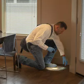 A uniformed technician from First Line Pest Defence conducting a thorough pest inspection for a residential client in Boise, Idaho. The image highlights our commitment to detailed and professional service, ensuring all potential pest entry points, like this floor vent, are carefully examined. We specialize in residential and commercial pest control, offering services for common Idaho pests including ants, spiders, rodents, and wasps. Our methods are safe for your family and pets.