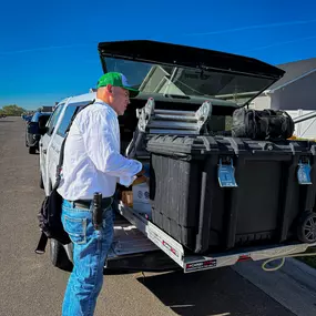 A First Line Pest Defense technician accessing equipment from the service truck, preparing for a pest control job.