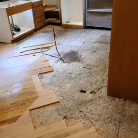 Pictured here is Siren Wisconsin water damage in a kitchen.  In this picture, you can see we are drying out the tongue and groove hardwood floor panels.