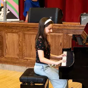 A young student plays the piano confidently on stage, reflecting the supportive and creative learning approach of Musicolor Method NYC and its engaging piano lessons for kids.