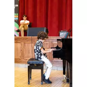 A child plays the piano onstage with focus and confidence, reflecting Musicolor Method NYC’s approach to fun music learning for kids.