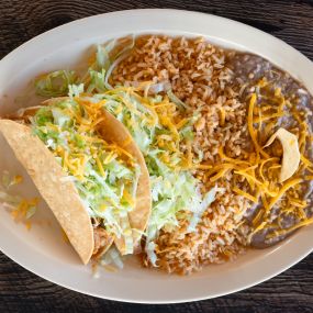 2 Crunchy chicken Tacos topped with crisp lettuce and fresh Cheddar Cheese and all served with a side of seasoned rice and refried beans.