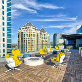 A rooftop patio with yellow chairs and a fire pit