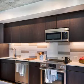 A modern kitchen with dark wood cabinets and stainless steel appliances