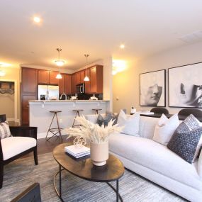 A living room with a white couch and a table with a vase of flowers on it