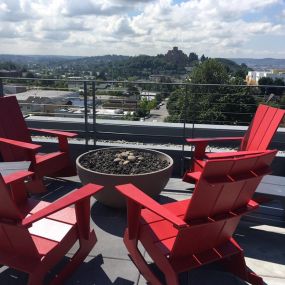 Red adirondack chairs surrounding a fire pit on the rooftop at Decibel on 12th