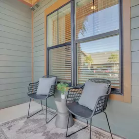 A patio with two chairs and a window