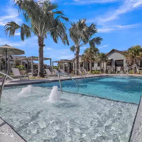 A swimming pool with palm trees and houses in the background