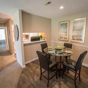 Dining area with hardwood-style floor and overhead lighting beside kitchen