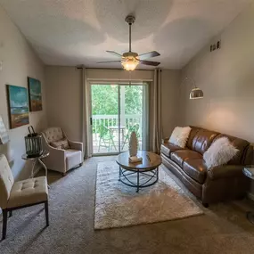Living room with illuminated ceiling fan and sliding glass doors to deck