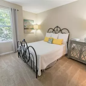 Bedroom with plush carpeting, large window, and model furnishings
