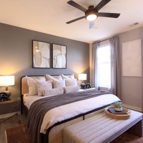 A bedroom with a ceiling fan and two windows