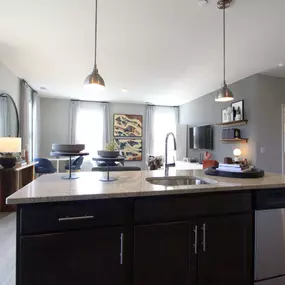 A kitchen with a large island and a living room in the background