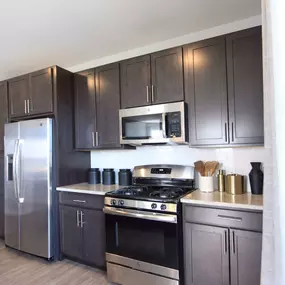 A kitchen with dark cabinets and stainless steel appliances