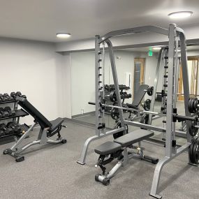 Fitness center with weight rack, free weights, squat, bench press rack, and two benches