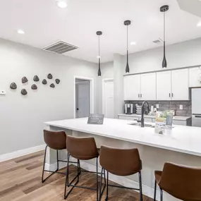 A kitchen with white countertops and brown chairs