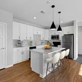A kitchen with white cabinets and a white island with three bar stools