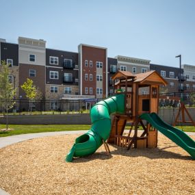 A playground with a slide in front of an apartment building