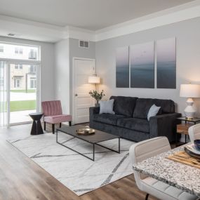 A living room with a couch table and chairs and a sliding glass door leading to a balcony