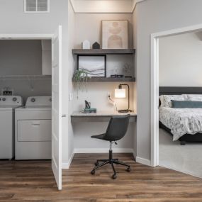 A bedroom with a desk and a washer and dryer