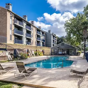 A swimming pool with chaise lounge chairs and a building in the background