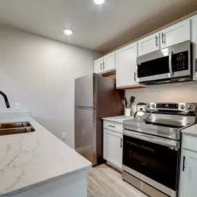 a kitchen with white cabinets and stainless steel appliances