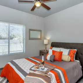 Cozy Bedroom with Brightly Colored Bedding, a Ceiling Fan, and Plank Flooring