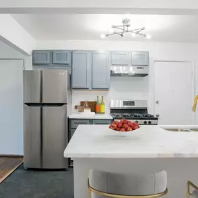 a kitchen with a marble counter top and stainless steel refrigerator