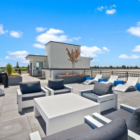 a rooftop patio with lounge chairs and tables