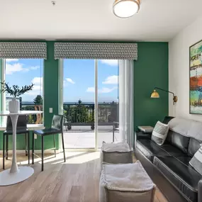 a living room with green walls and a sliding glass door that leads to a balcony
