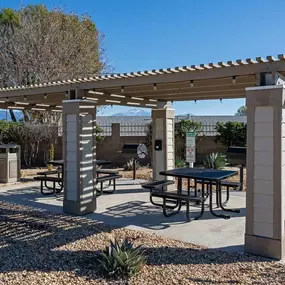 a picnic area with a table and benches under a pergola