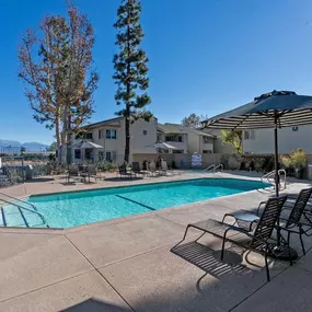 a swimming pool with chaise lounge chairs and umbrellas