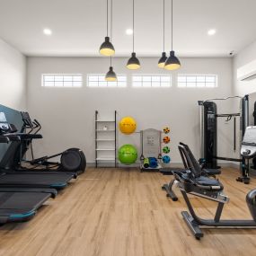 a gym with treadmills and weights on a wooden floor